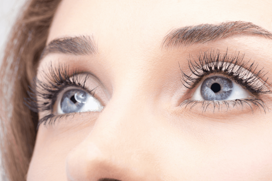 A close up of a woman 's blue eyes with long eyelashes.